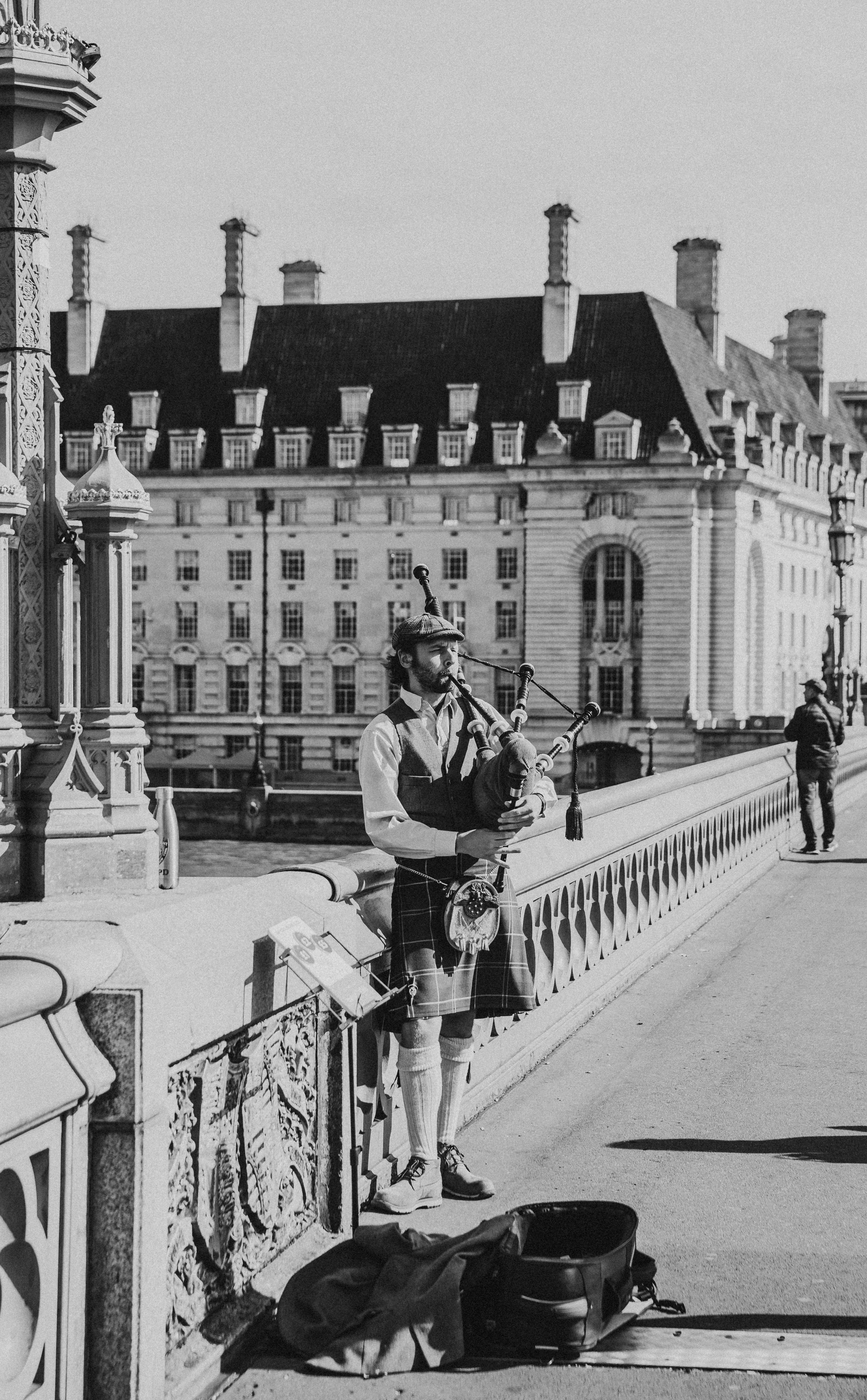 A bagpipe busker playing on a bridge in London